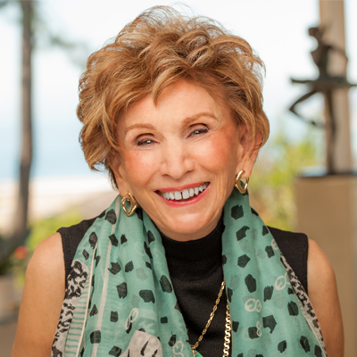 Een lachende Edith Eger met een sjaal om haar nek